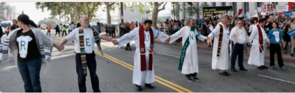 [This photo is from an action in southern California, where clergy took a stand against family separation at the US-Mexico border.]