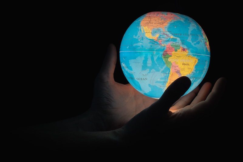 Shadow hands holding lit globe in their hands