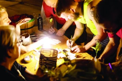 Group of people writing no leaves under a light