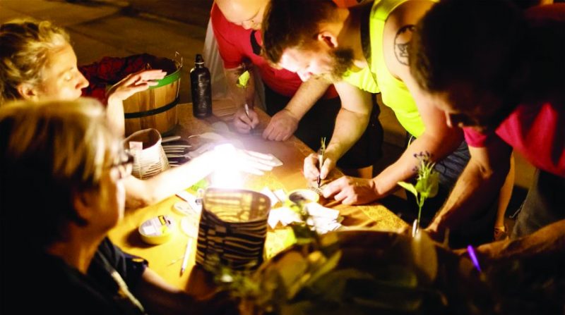 Group of people writing no leaves under a light