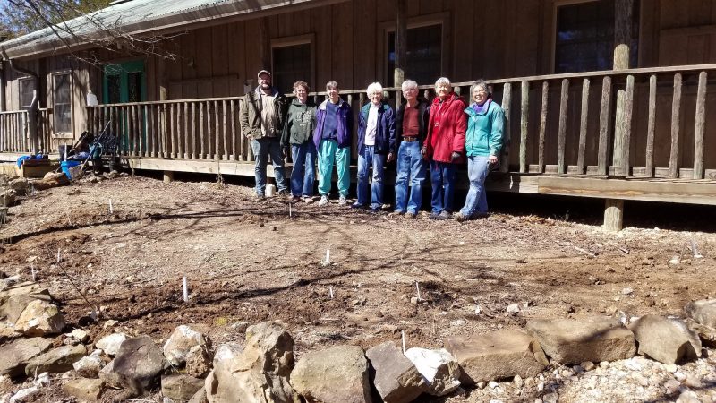 Seven people stand in soil