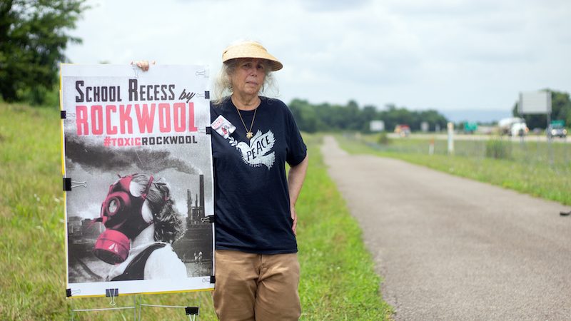 Bobbi Block holding up Rockwool protest poster next to country road