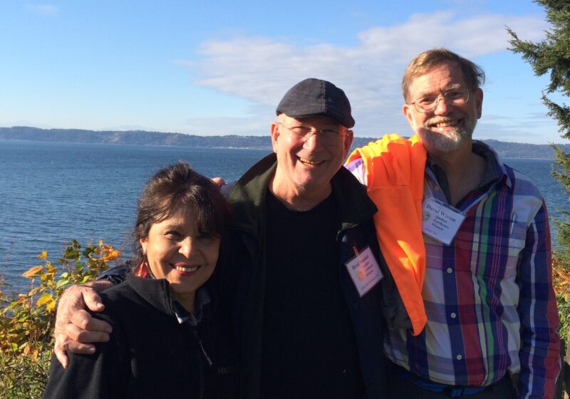 Three smiling people in front of ocean