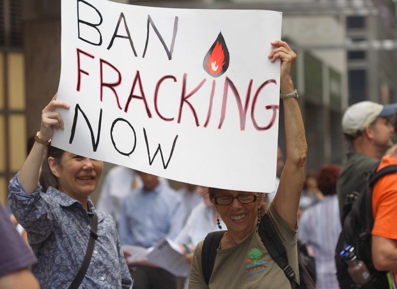 Two people holding sign that says Ban Fracking Now