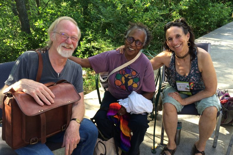 Three smiling people sitting in chairs outside