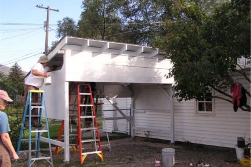 Person on ladder next to white wooden structure