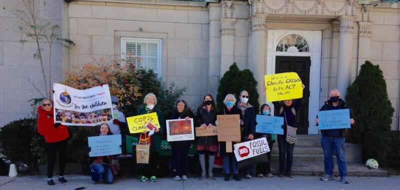 About a dozen people standing outside with climate change signs