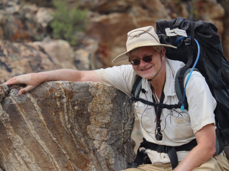 Al McGrew. Older white man in hiking gear next to a rock